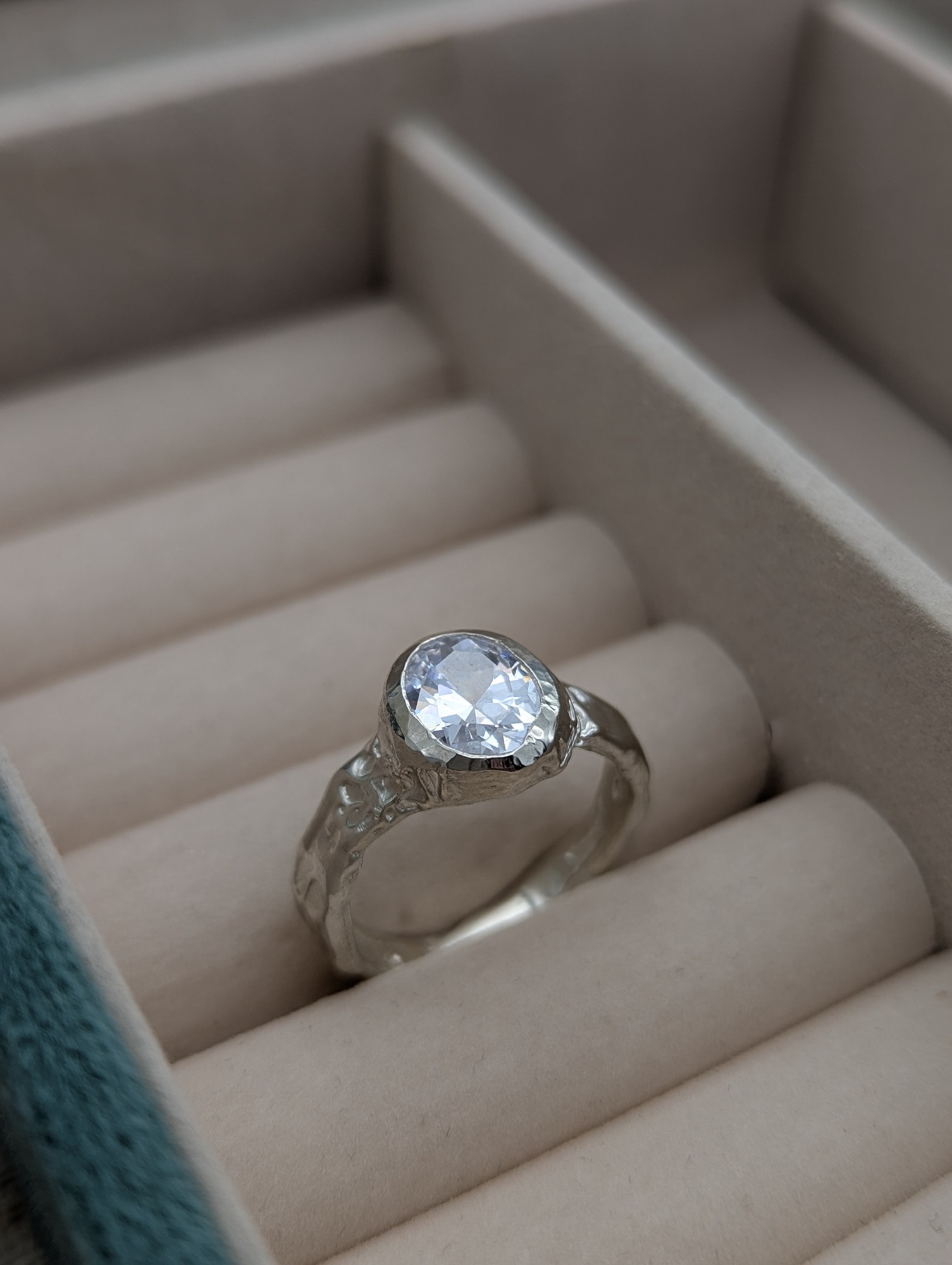 A CZ facet gemstone and sterling silver unique ring resting in a jewellery box