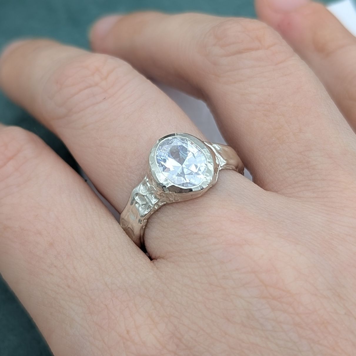 A cz facet gemstone and silver ring being worn on hand