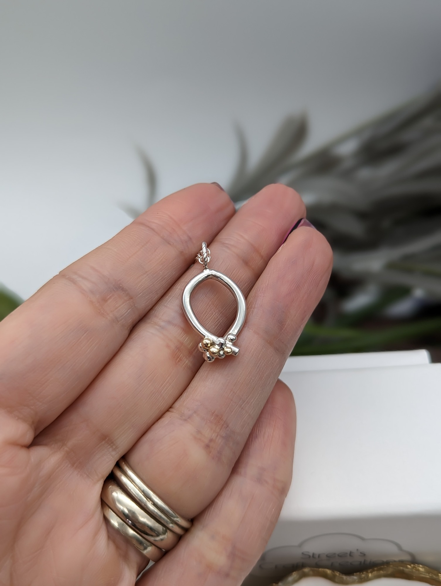 Silver & Gold granulation necklace held on a hand 