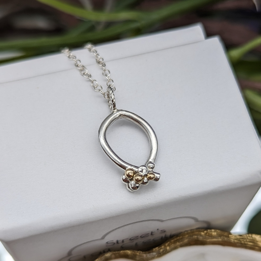 Silver & gold granulation necklace on a white jewellery box 