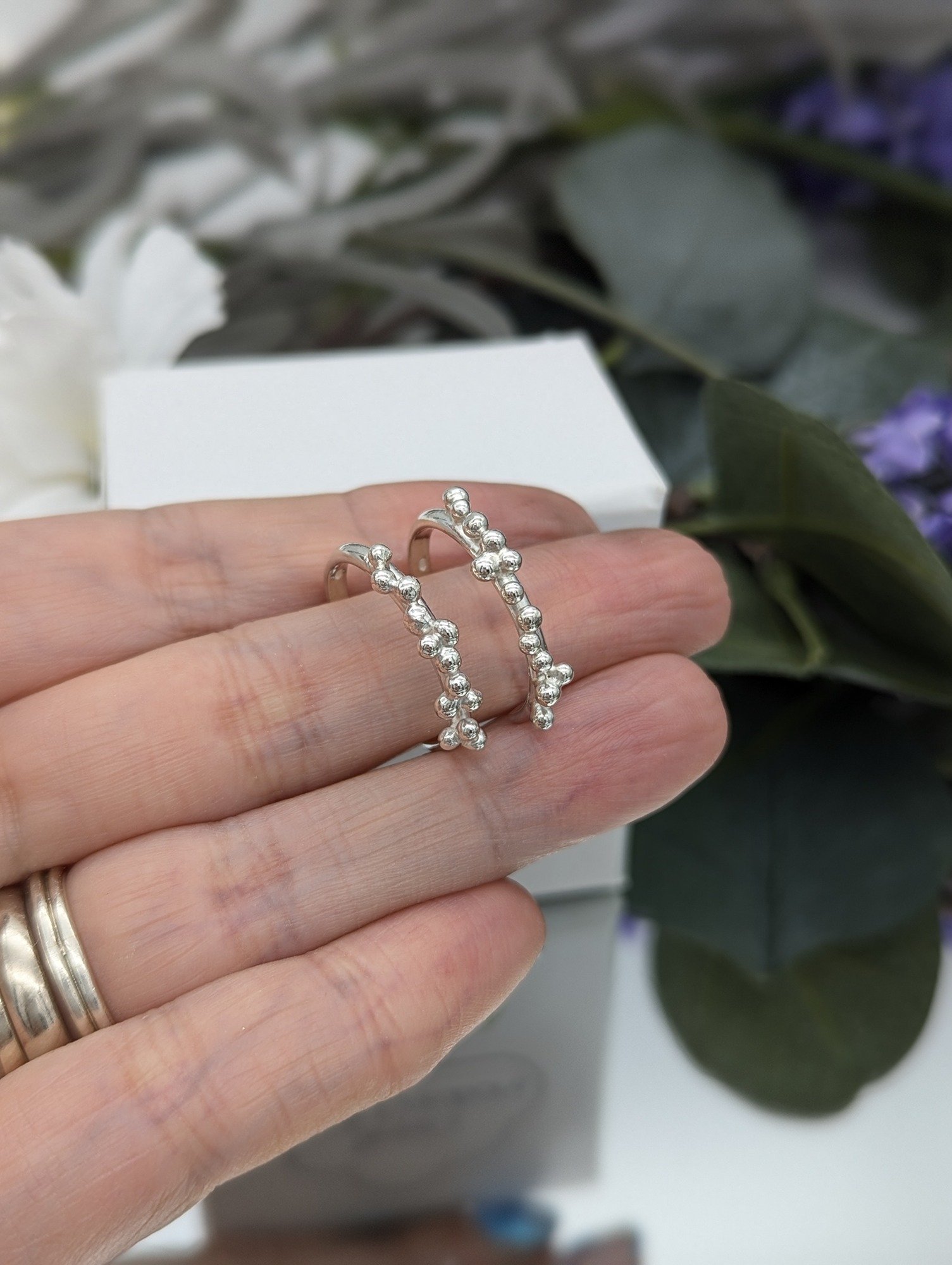 Silver Granulation half hoop earrings held on a hand