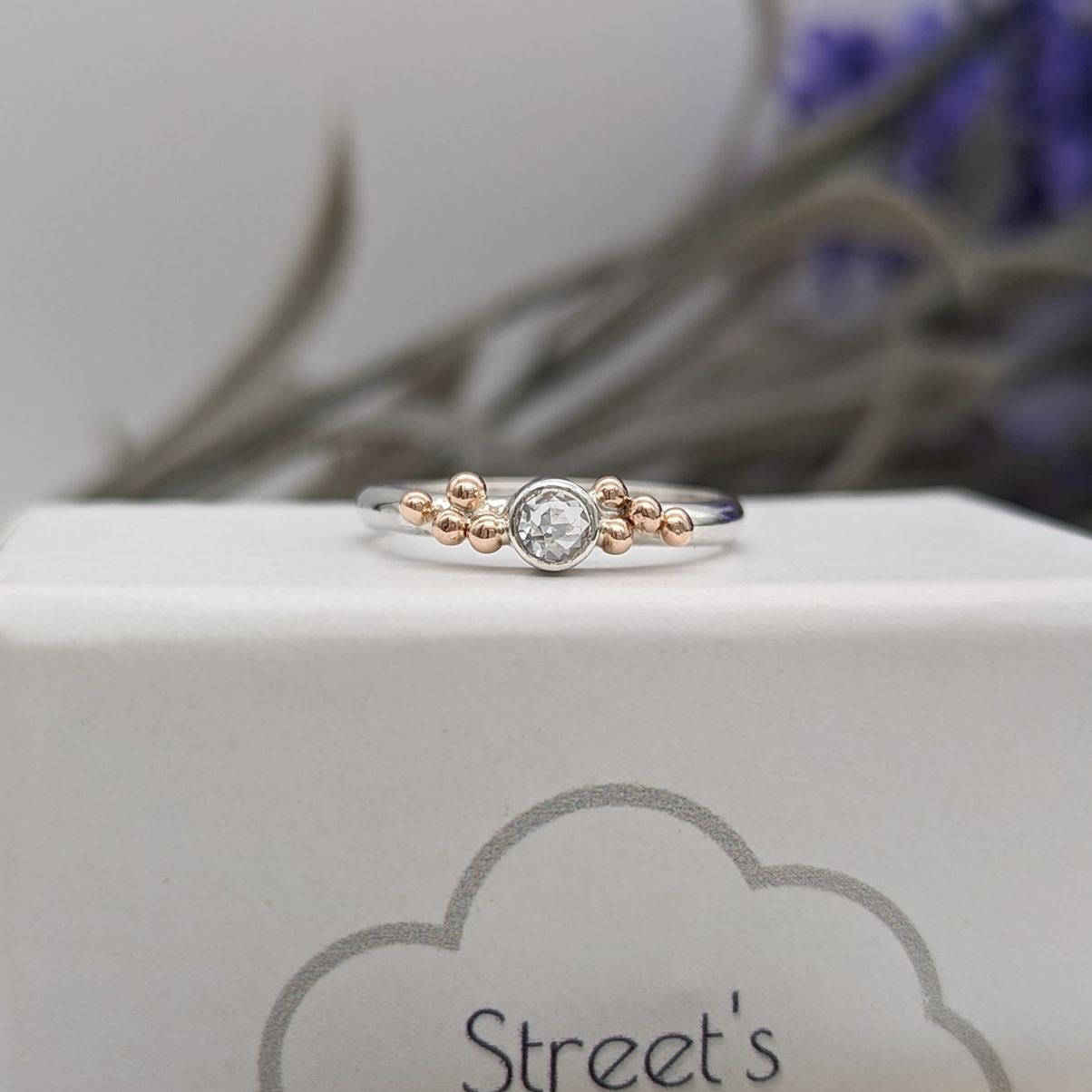 White topaz and rose gold granulation ring resting on a white jewellery box