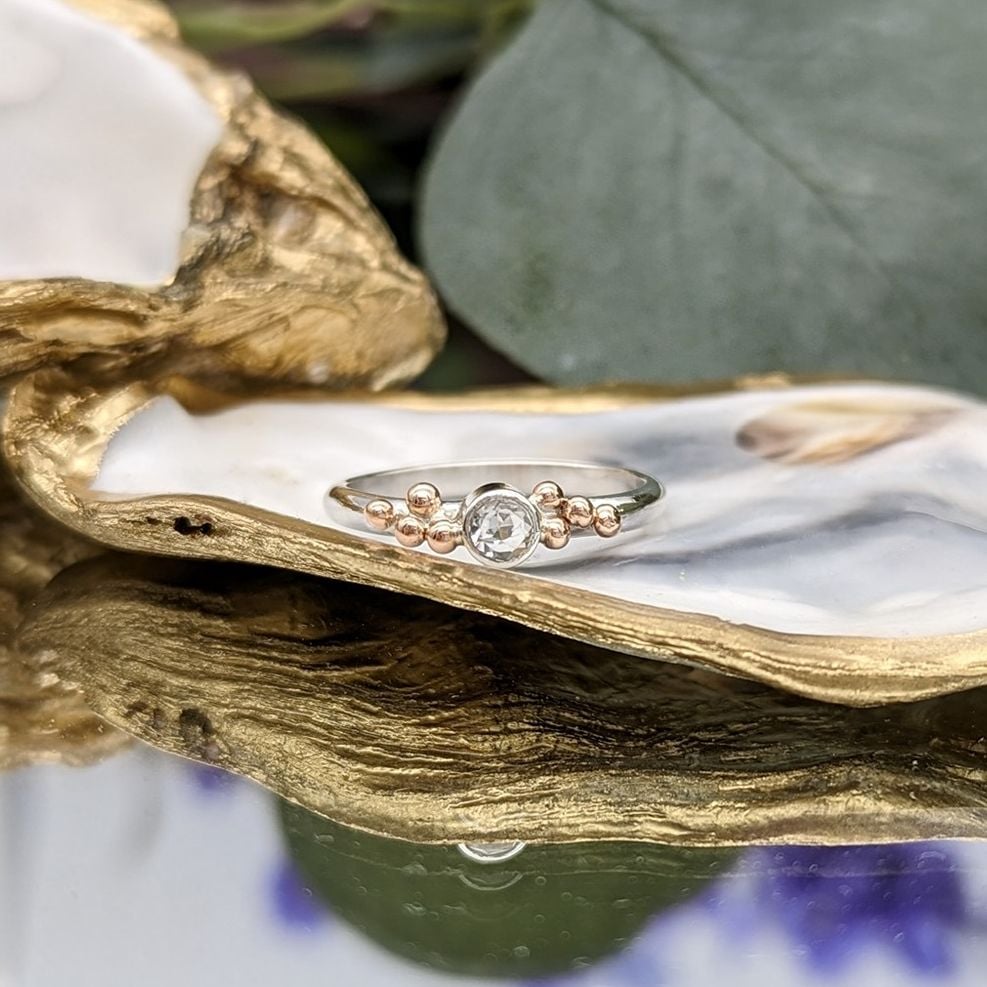 White Topaz and Rose gold granulation ring resting on a gold gilded oyster shell