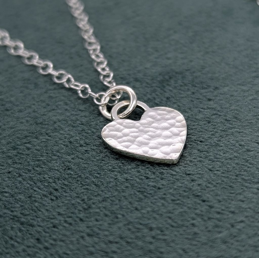 Textured silver heart necklace on a teal jewellery box