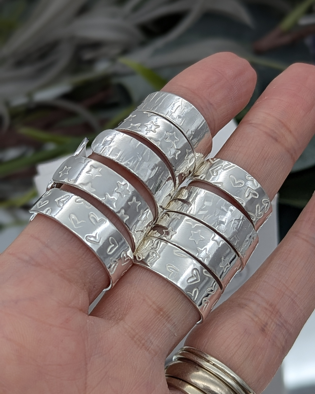 A selection of silver cuff rings on a hand
