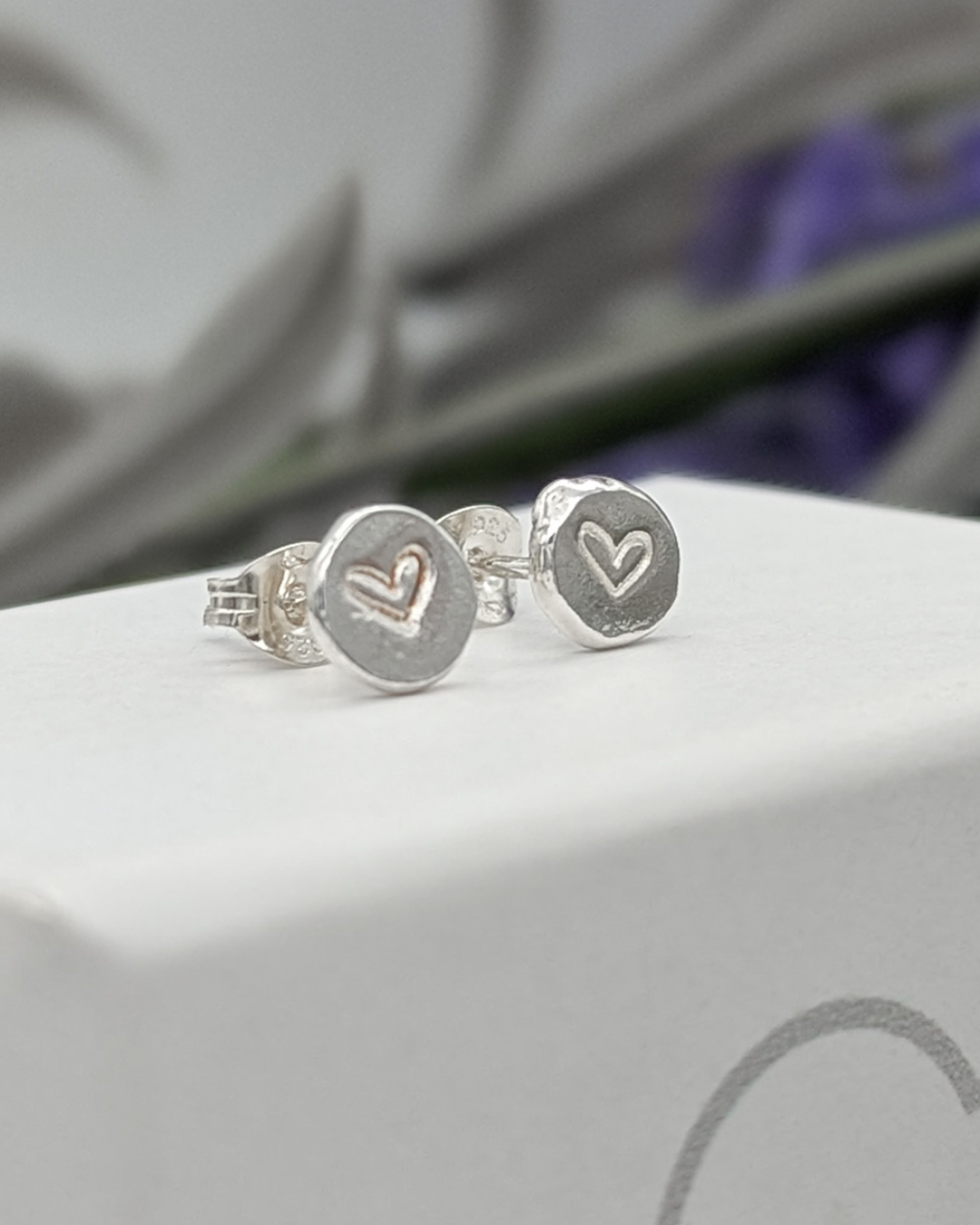 a close up of silver heart stamped stud earrings
