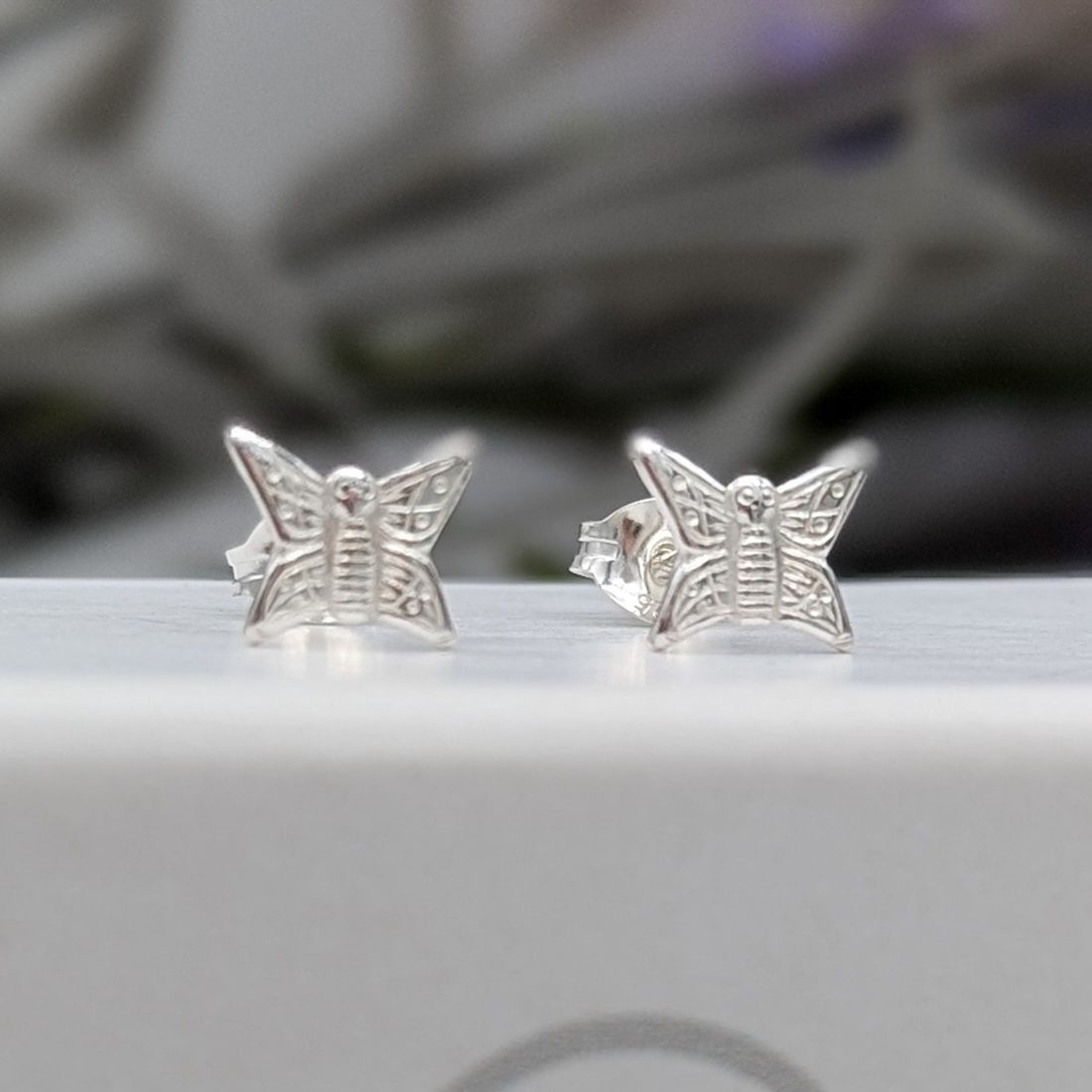 Silver butterfly stud earrings on a white jewellery box