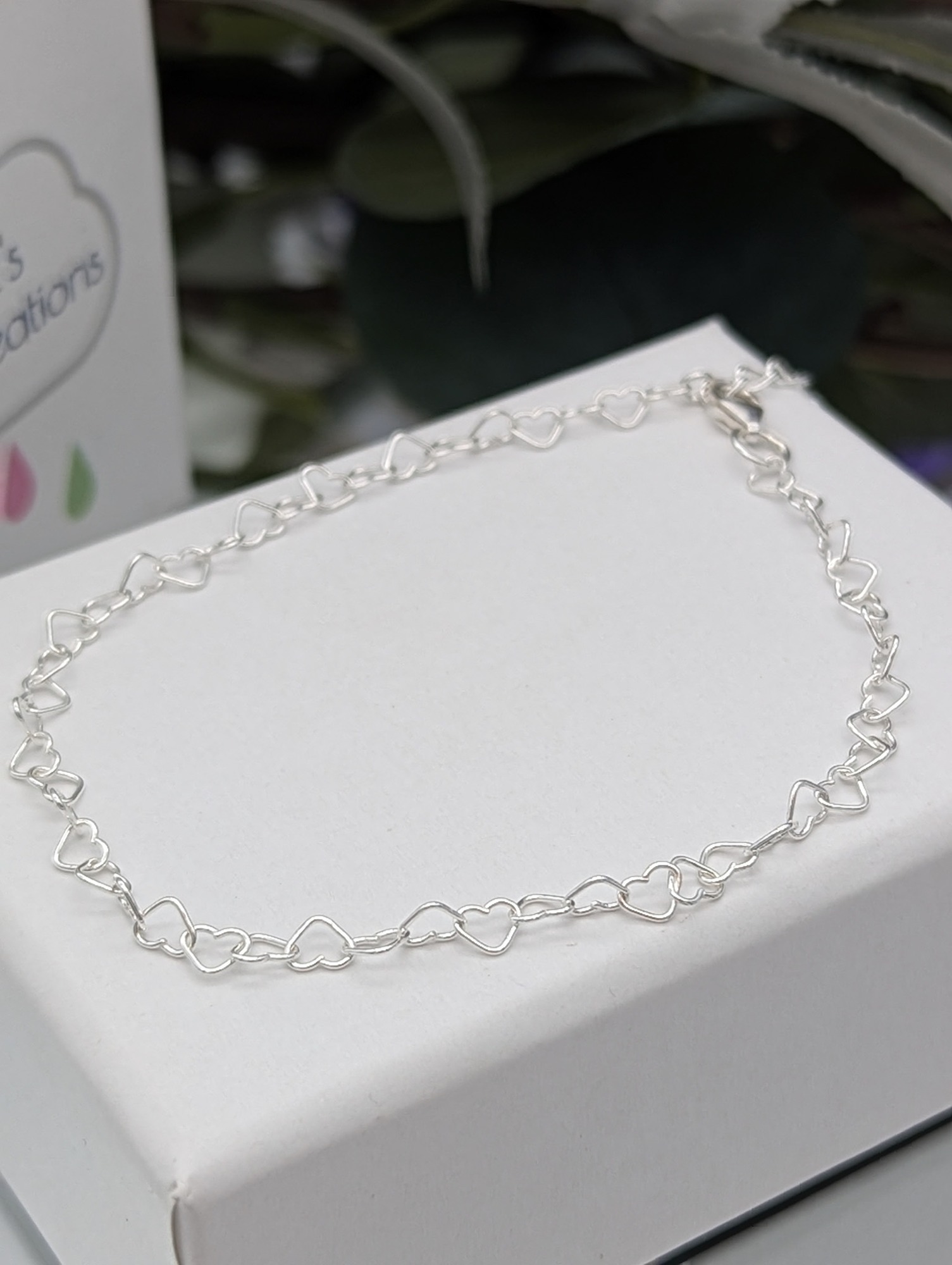 silver heart bracelet resting on a white jewellery box