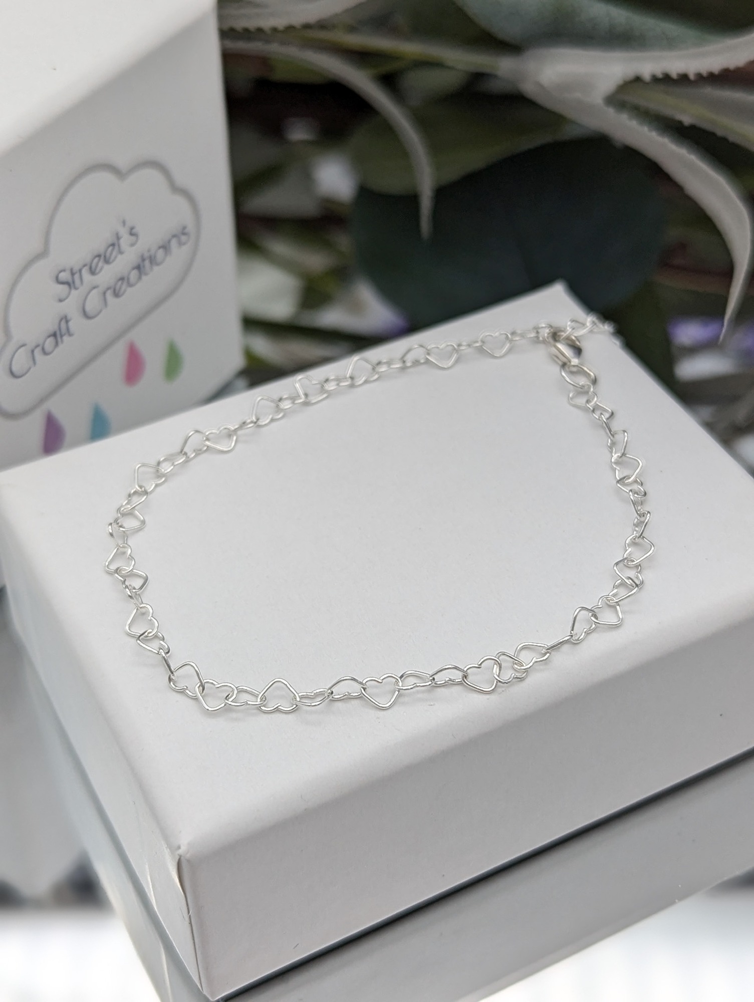 silver heart link bracelet on a white jewellery box