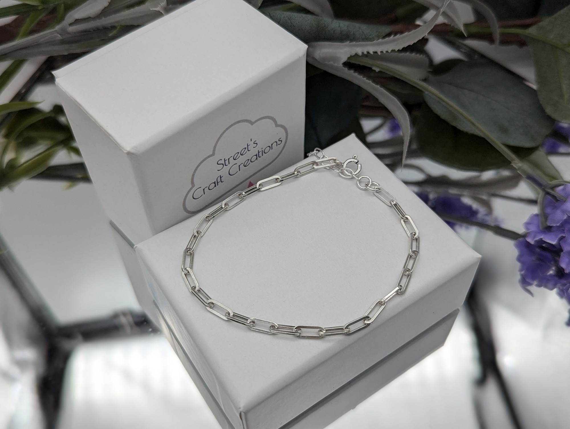 silver square link bracelet on a white jewellery box