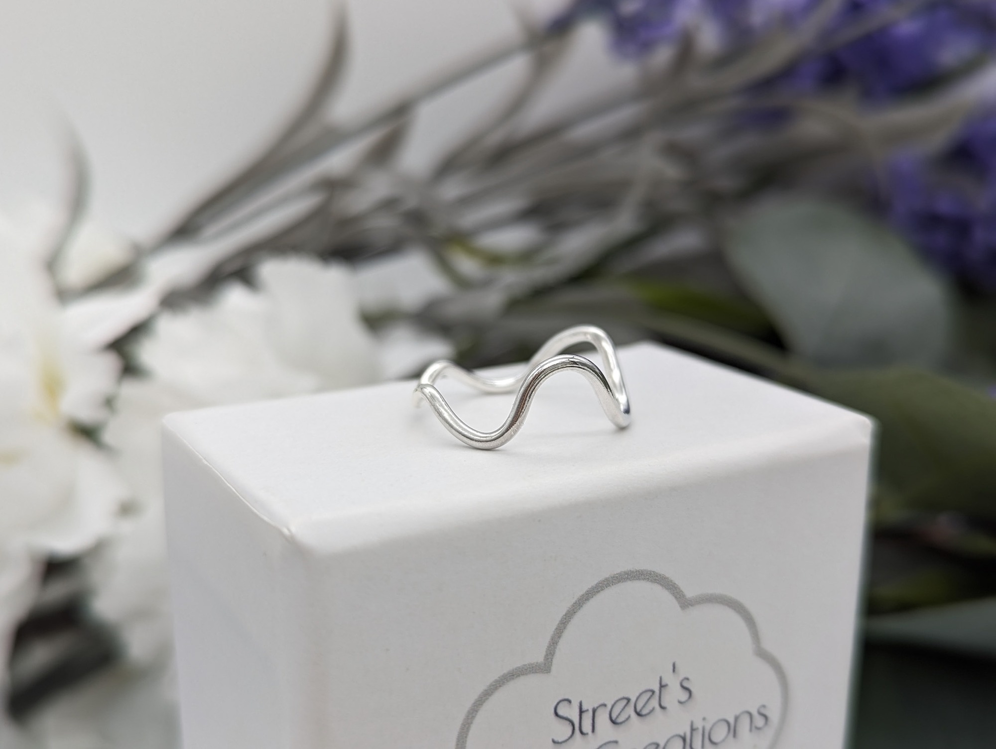a deep wave silver ring resting on a white jewellery box