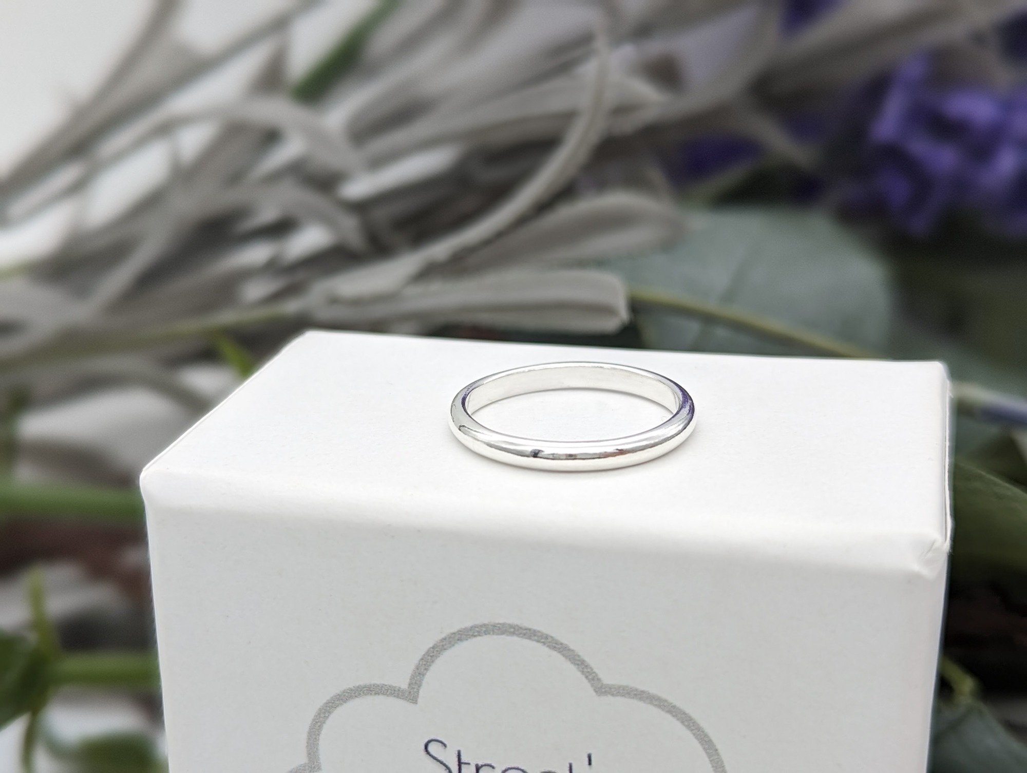 Silver D shape ring on a white jewellery box