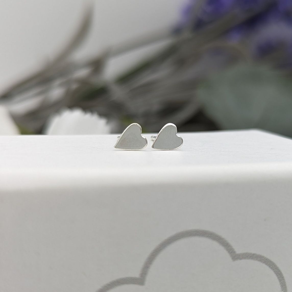 silver heart stud earrings on a white jewellery box