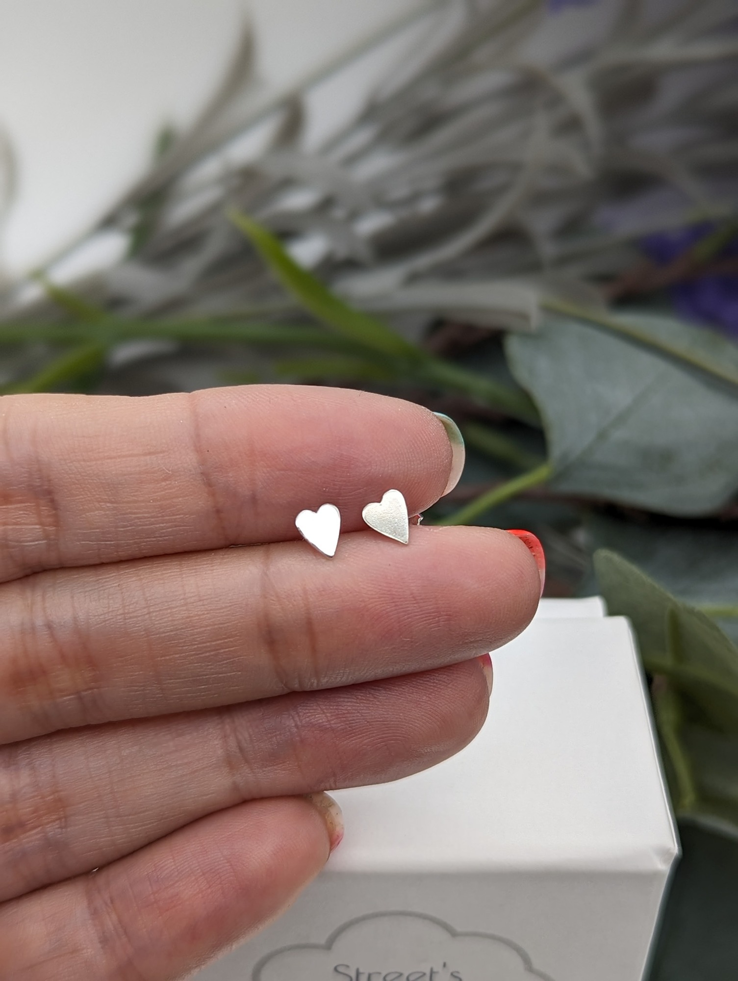 silver heart studs being held in a hand