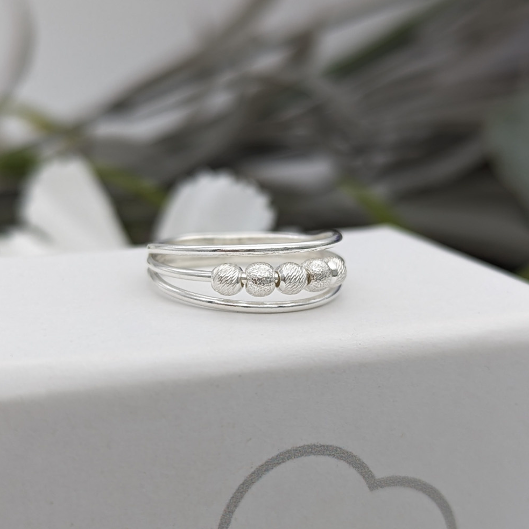 silver fidget ring resting on a white jewellery box