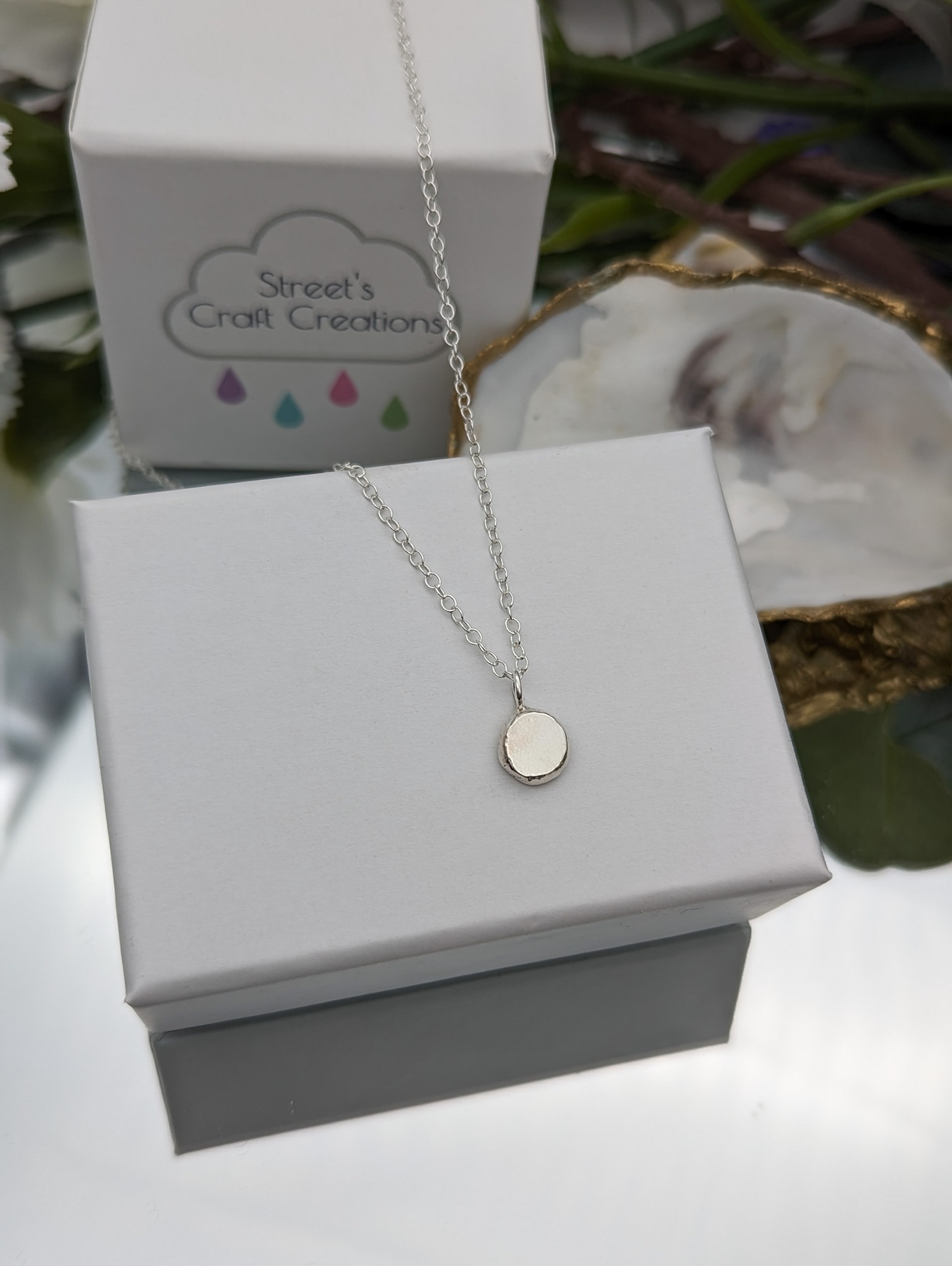 Silver droplet necklace on a white jewellery box