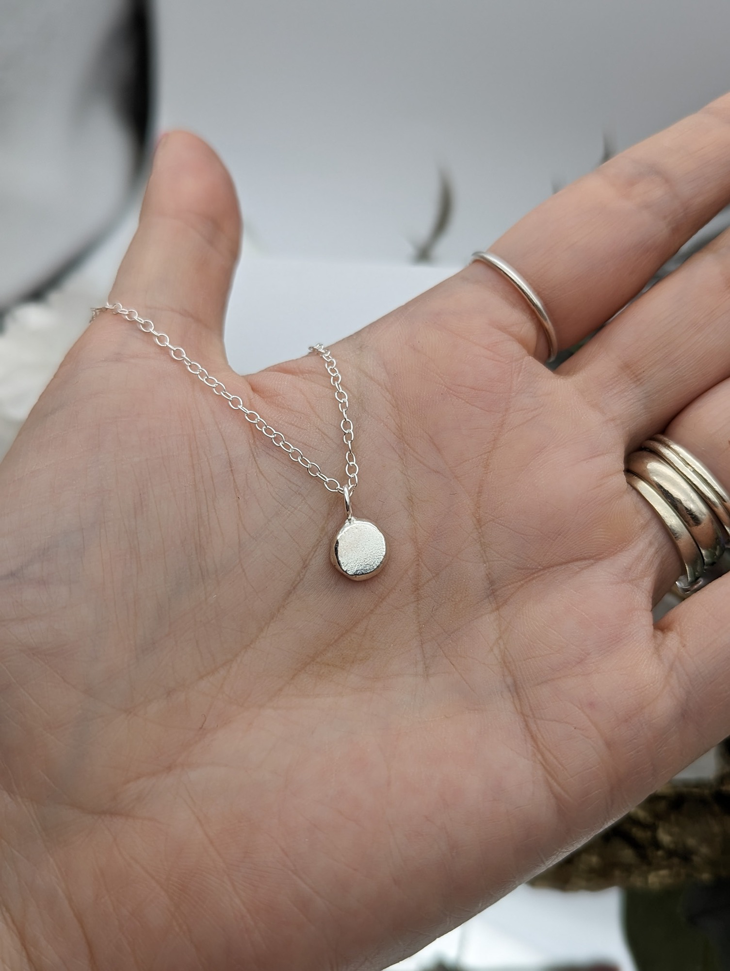 Sterling silver droplet necklace held in a hand
