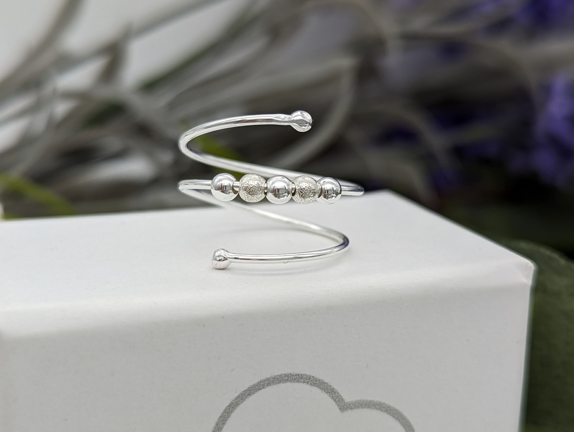 Silver fidget wrap ring on a white jewellery box