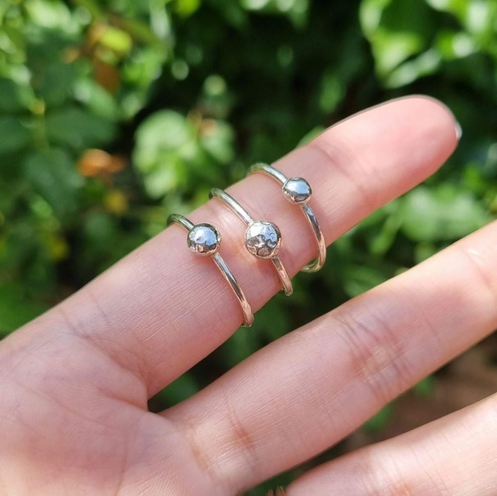 3 pebble rings on a hand with a leafy back ground
