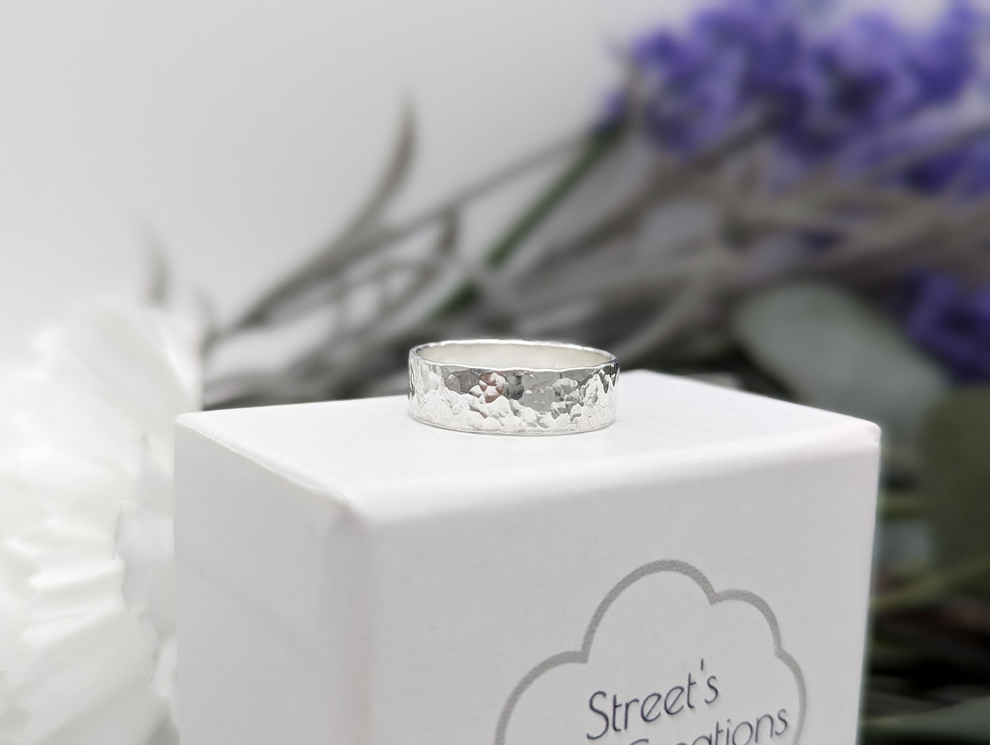 Silver hammered wide band ring on a white jewellery box