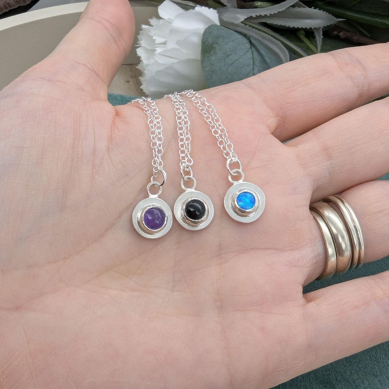 3 Gemstone dot necklaces resting on a hand 