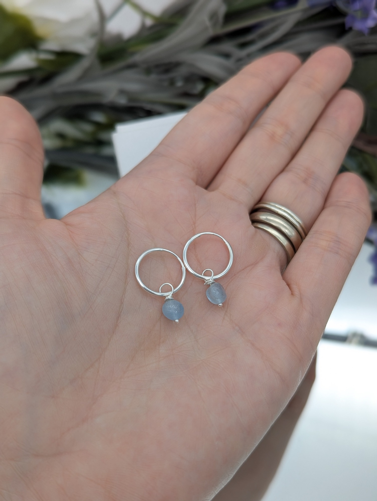 Aquamarine drop hoop earrings resting on a hand 