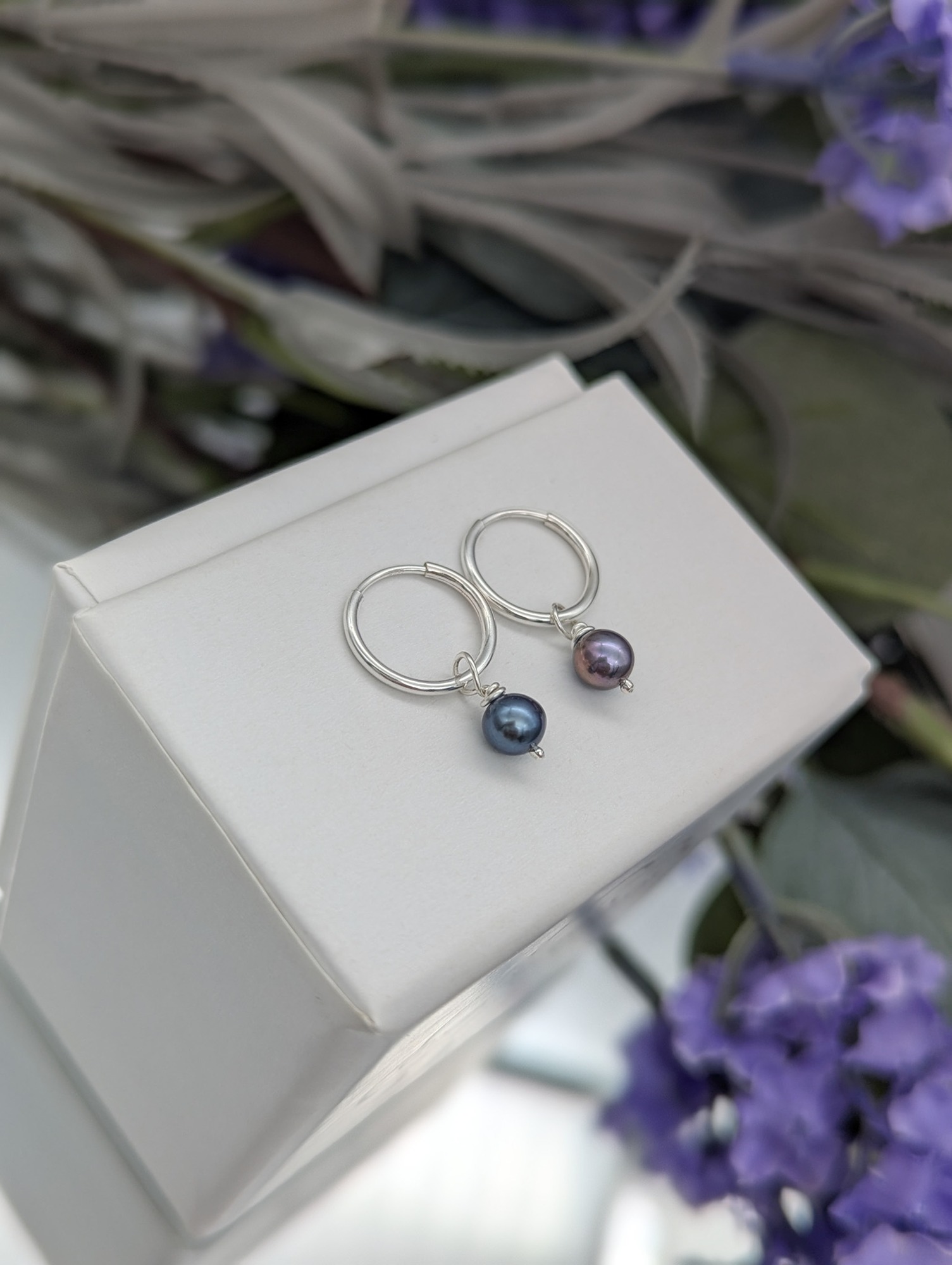 Peacock pearl hoops on a white jewellery box