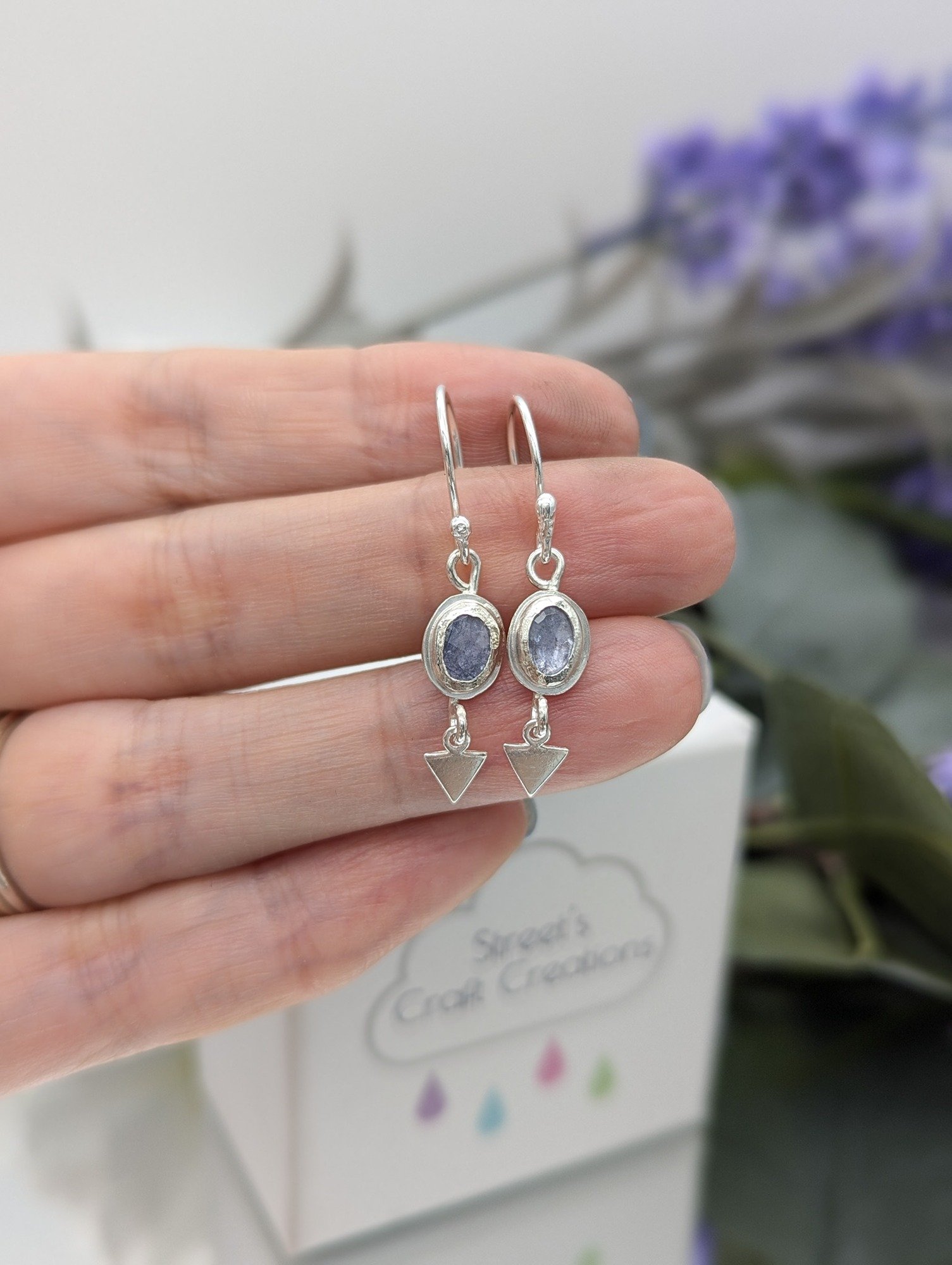 Tanzanite silver geometric earrings being held in a hand