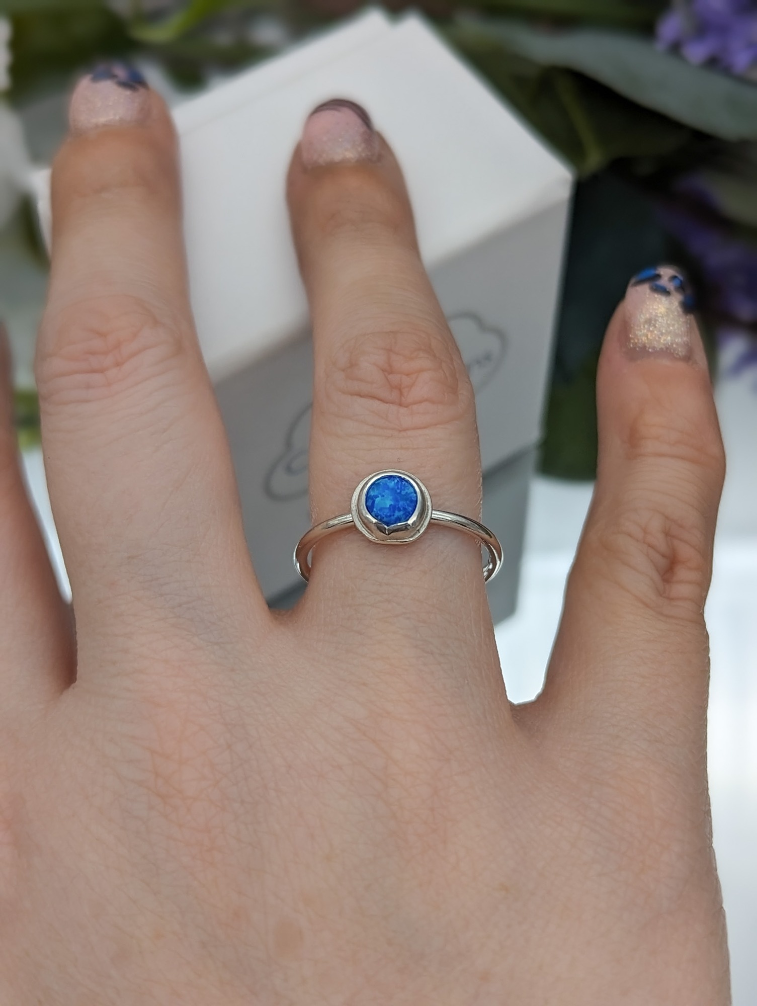 Created blue opal silver ring being worn on a hand
