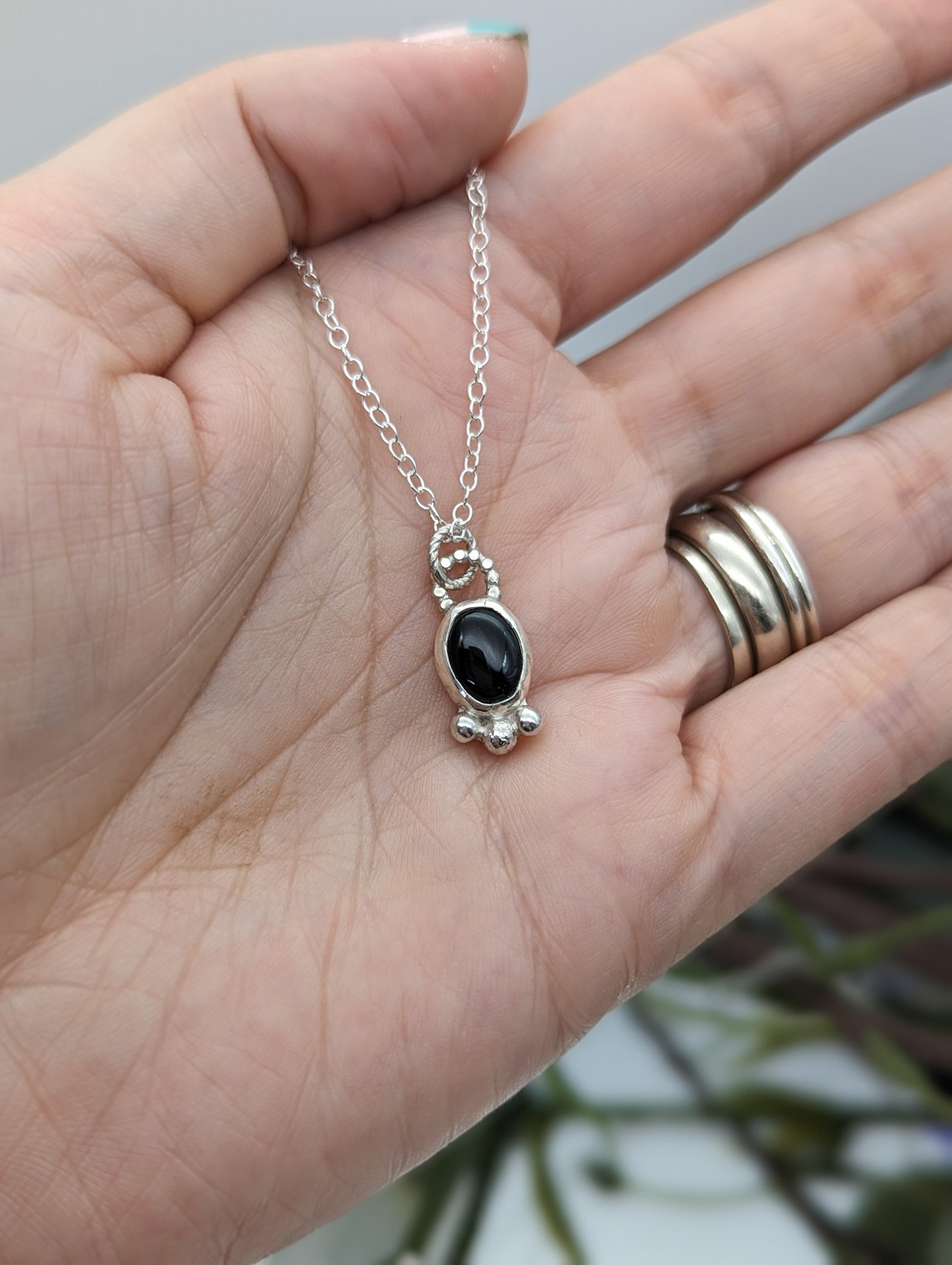 Silver & black onyx necklace on a hand