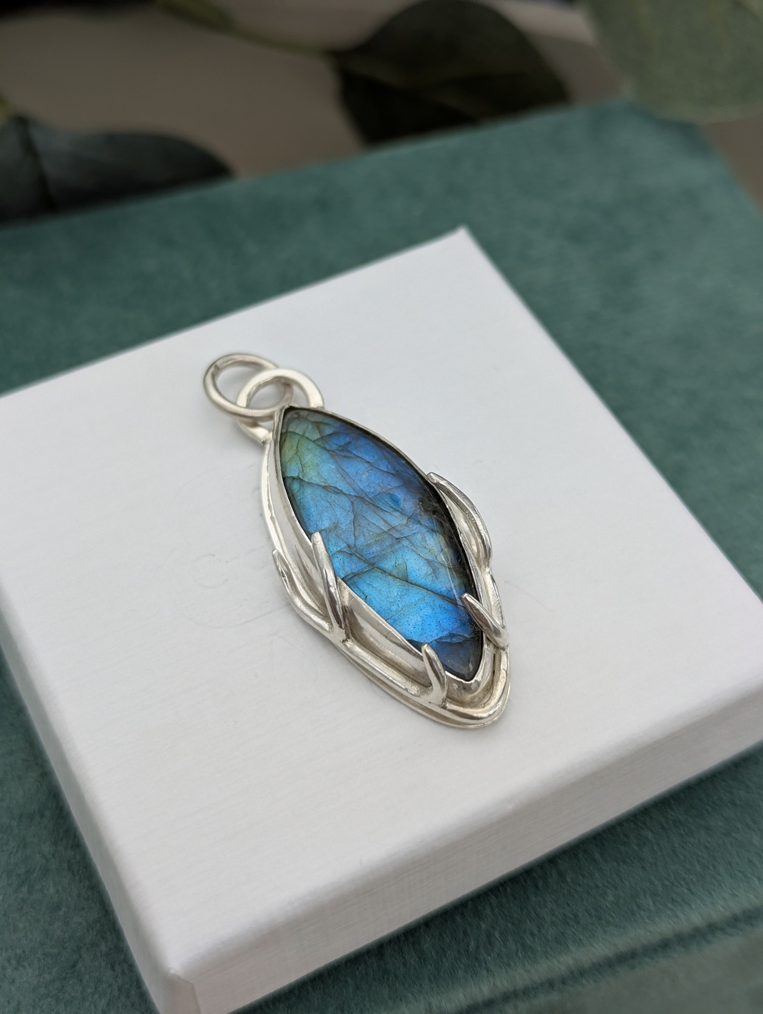 The labradorite pendant laying on an embossed white jewellery box