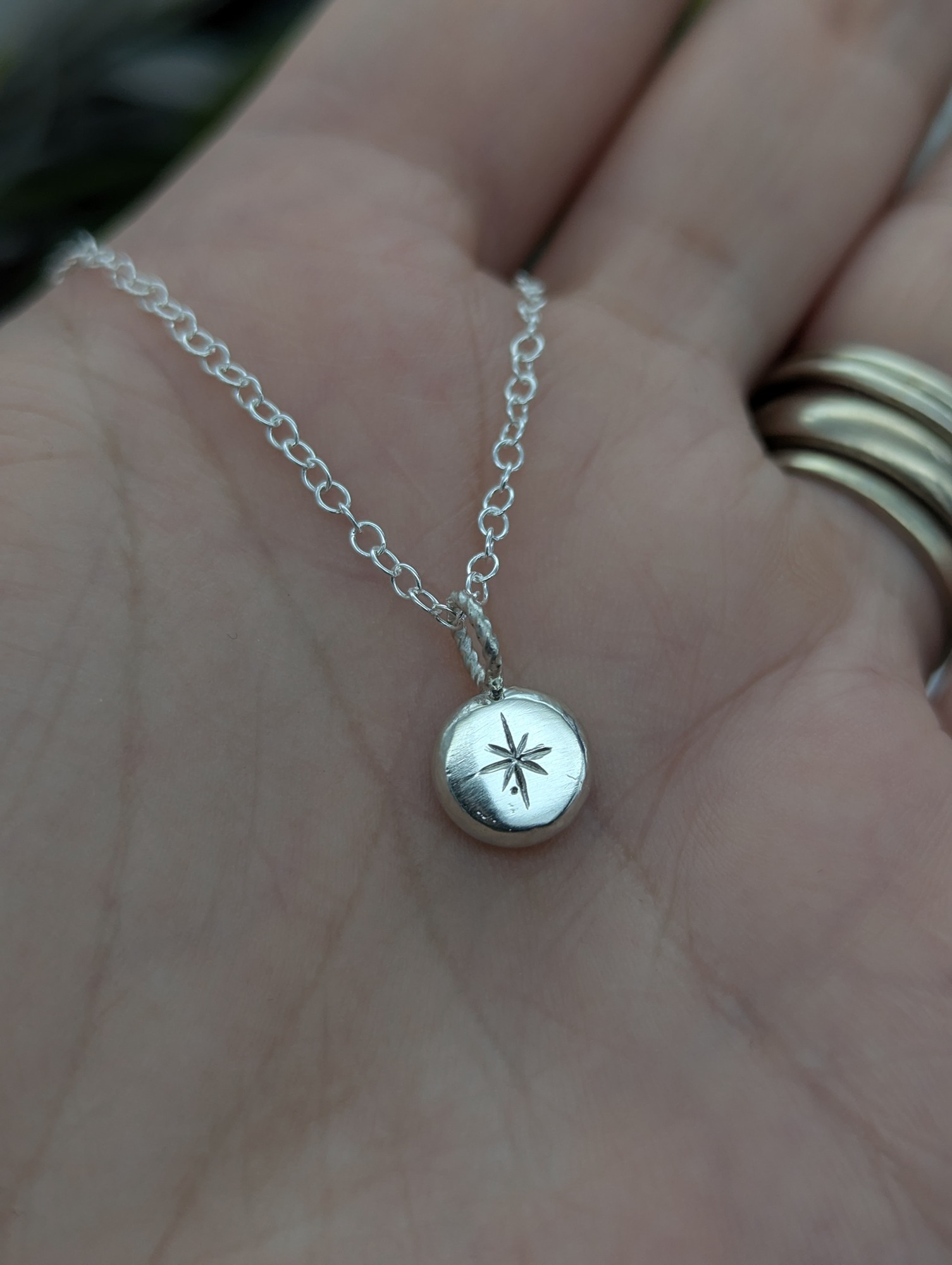 A close up of the North Star Necklace with details hand engraving