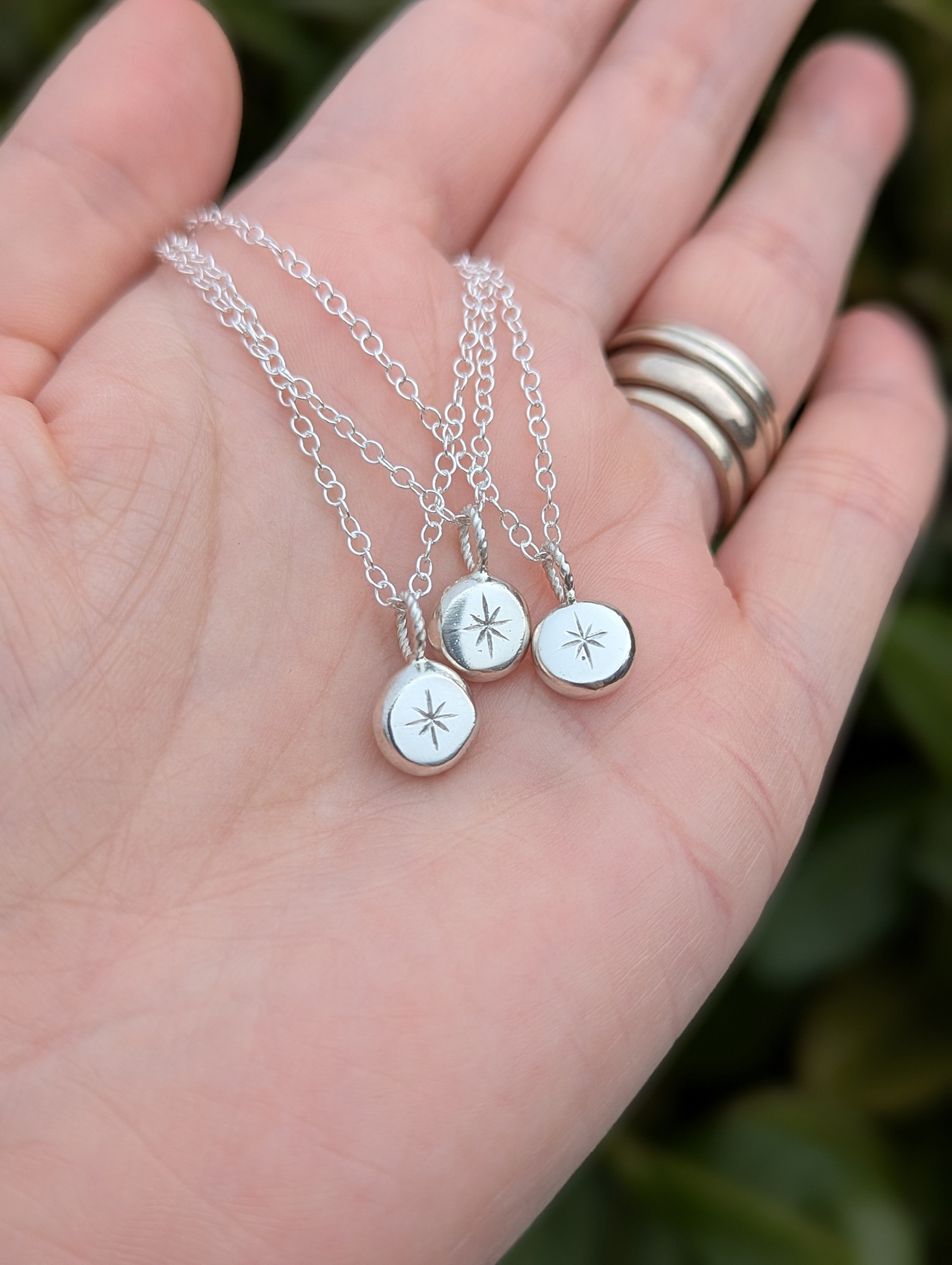 3 North Star necklaces resting on a hand