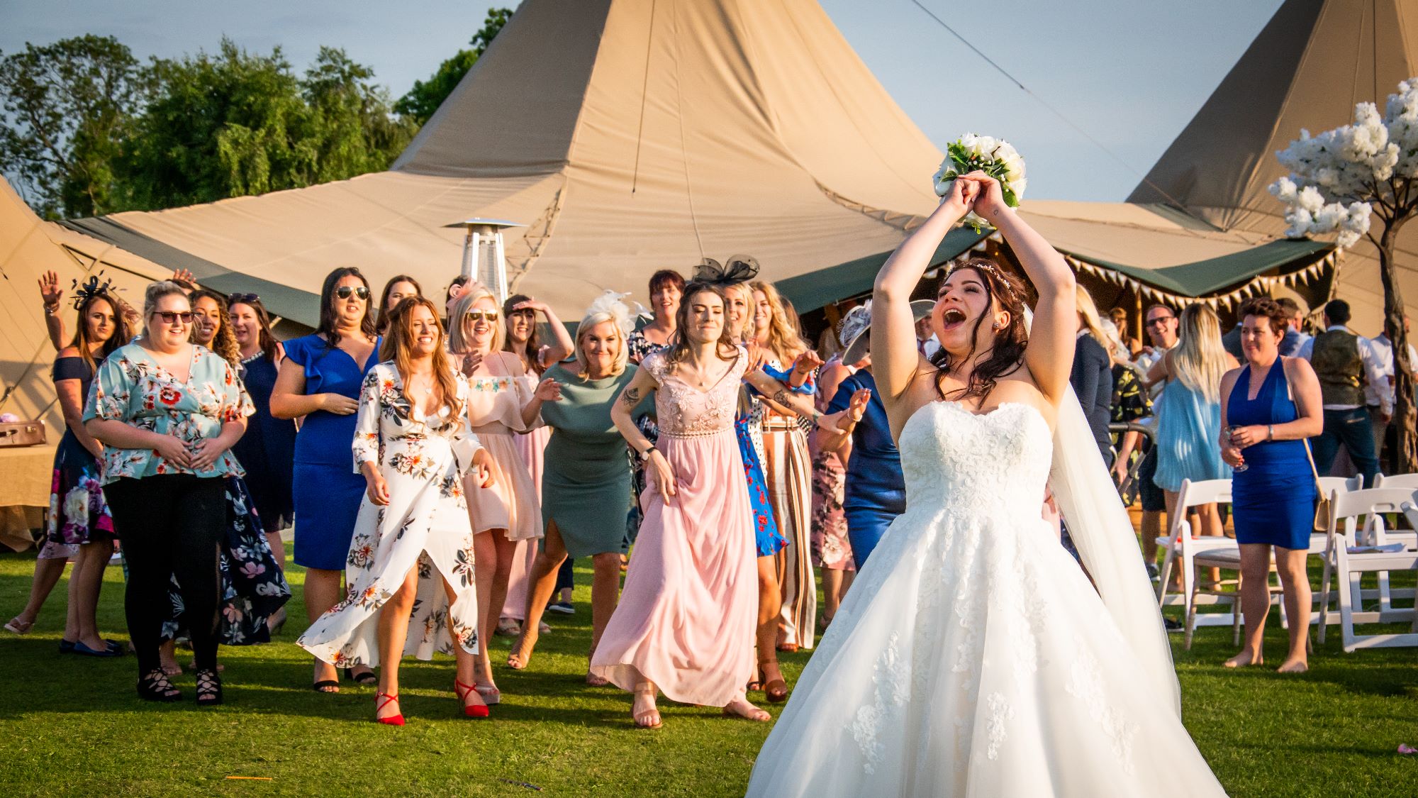 A bride gets ready to throw her bouquet at her wedding in Pickering, North Yorkshire. A group of women battle in hte background to be at the front ready to catch it.