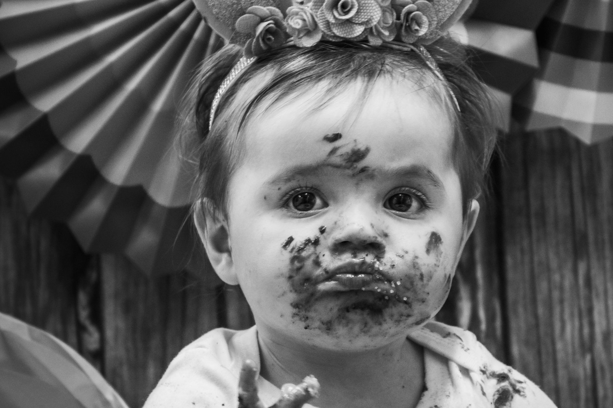 Cake smash first birthday celebration - a little girl is photographed with chocolate cake all over her face