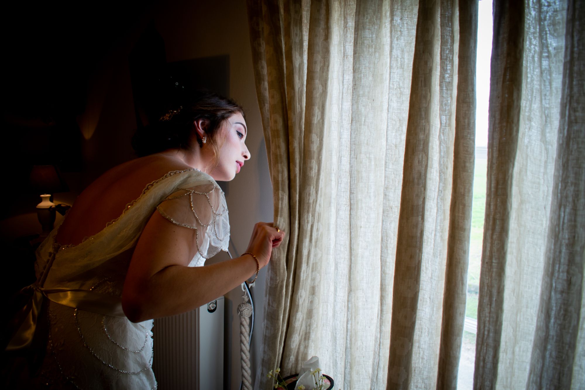 the bride peeps round the curtains to watcher her guests arrive before heading off to get wed in york