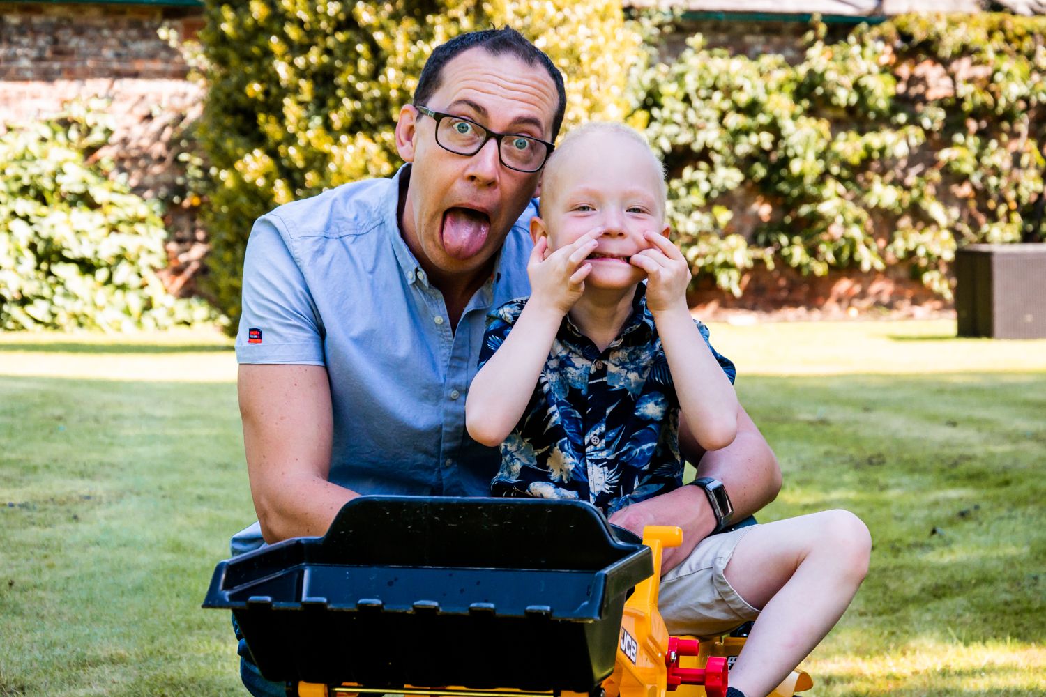 A father and son pull silly faces when they realise they are being photographed.