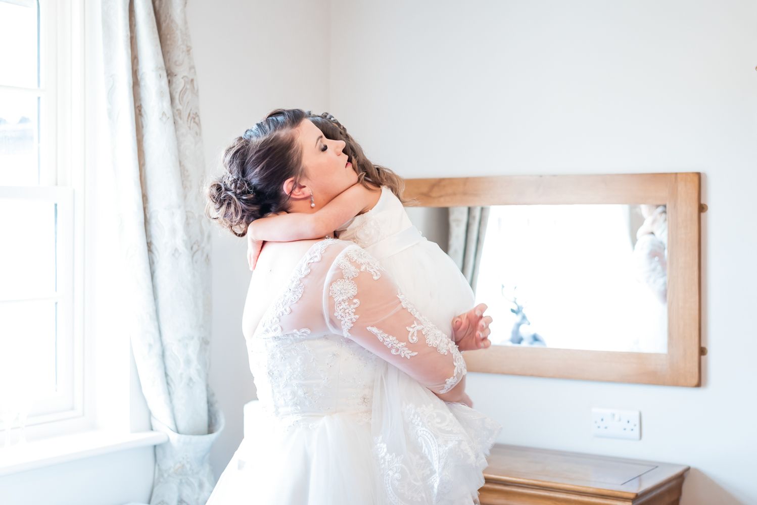 the bride hugs her daughter as they've both just finished getting ready on her wedding day.