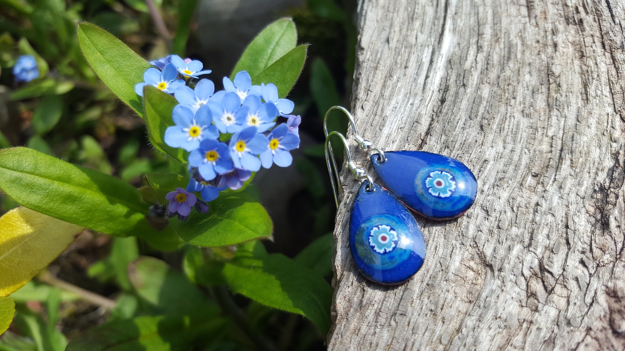 Teardrop enamel earrings, blue with a flower on sterling hooks. Shown alongside wild forget-me-not flowers in the same shade - the source of their inspiration