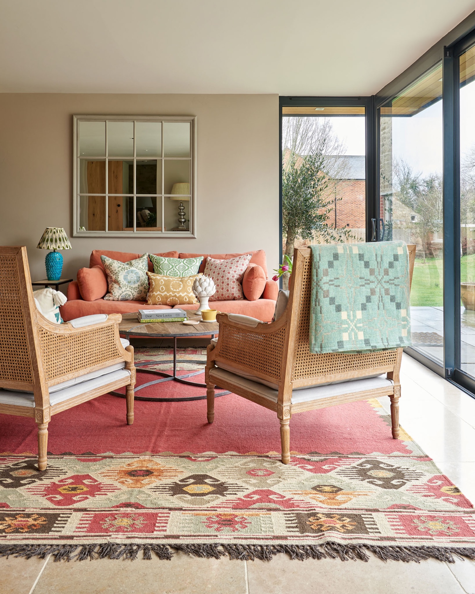 Colourful interior with printed cushions on a orange Loaf sofa. two nordic style chairs with a merlin tregwynt. painted walls using  little Greene paint