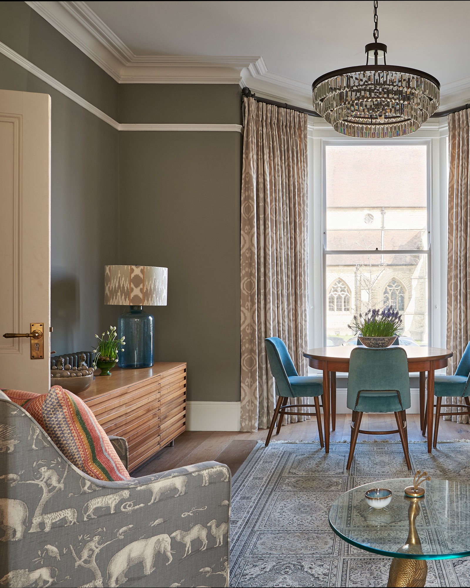 Beautiful Georgian town house painted in worsted farrow and ball, with styled book shelves and  Andrew Martin upholstered armchairs and cushions. Vintage dining table with bespoke dining chairs.