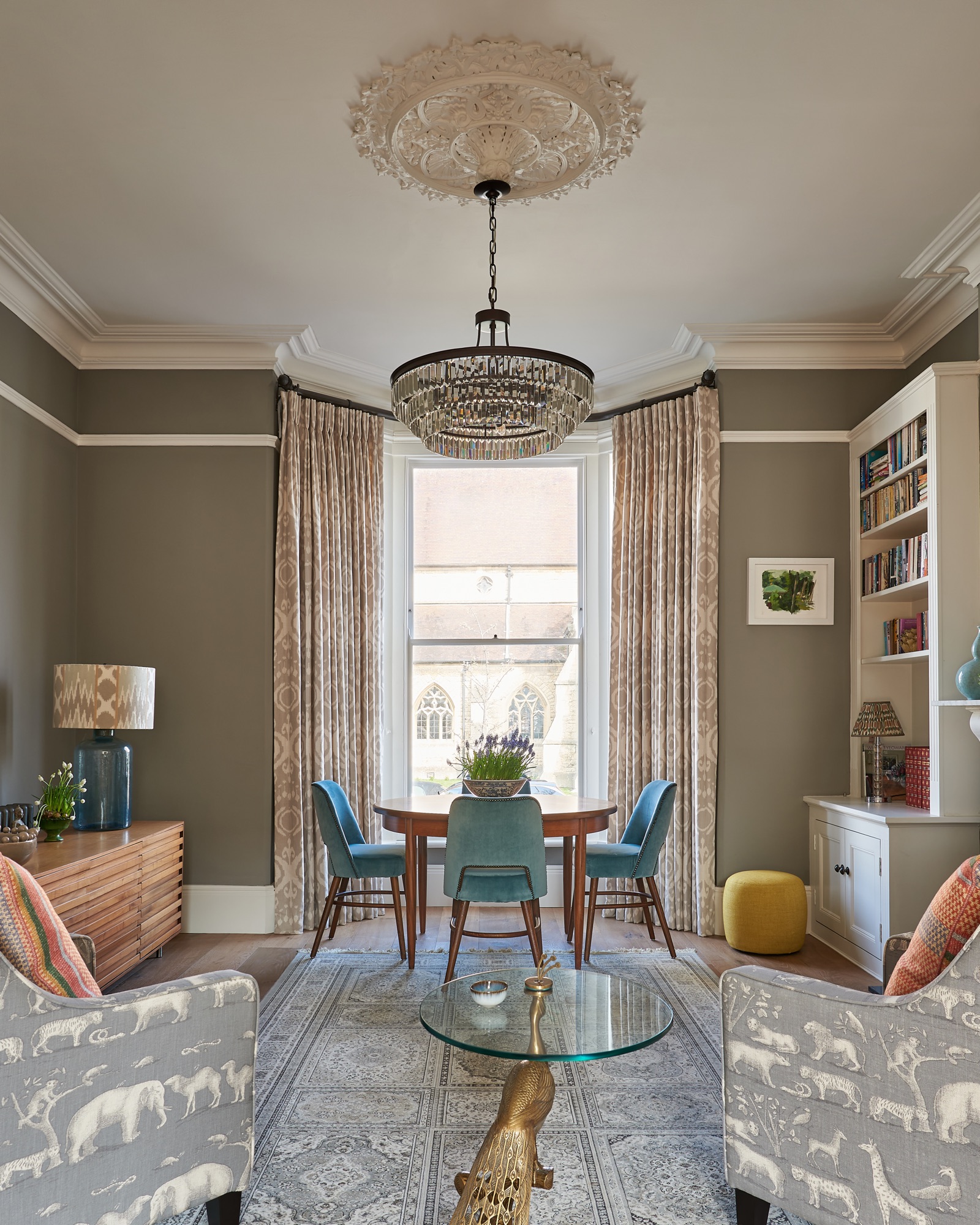 Beautiful Georgian town house painted in worsted farrow and ball, with styled book shelves and  Andrew Martin upholstered armchairs and cushions. Vintage dining table with bespoke dining chairs. Full length Andrew Martin curtains.