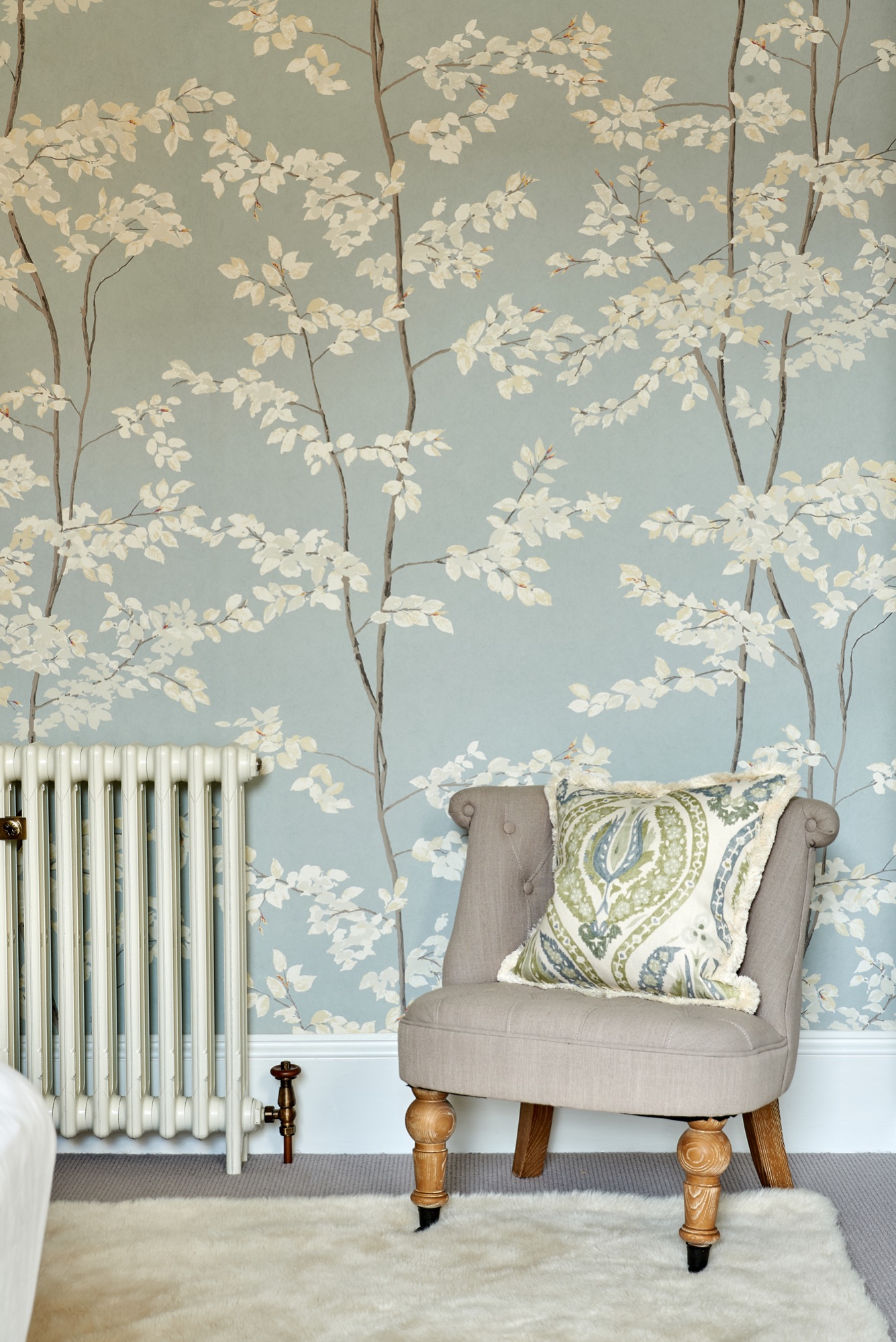 lewis and wood beech wallpaper with cast iron column radiator and small button back chair from one.world. Elizabeth Violet home bespoke cushion using lewis and wood fabric.
