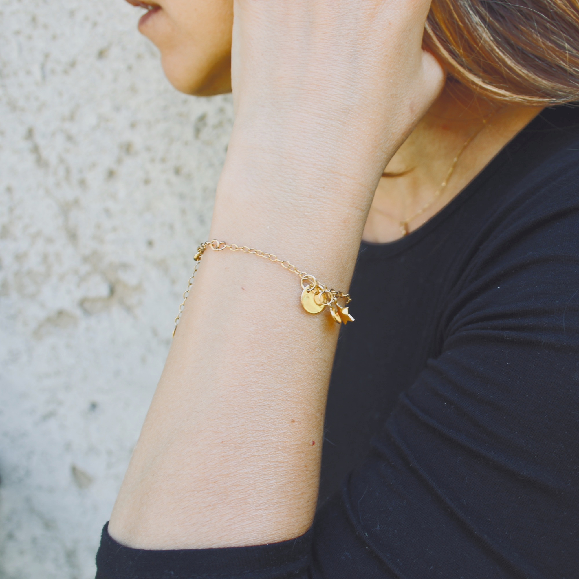 a model featured a hand with gold bracelets with gold charms 
