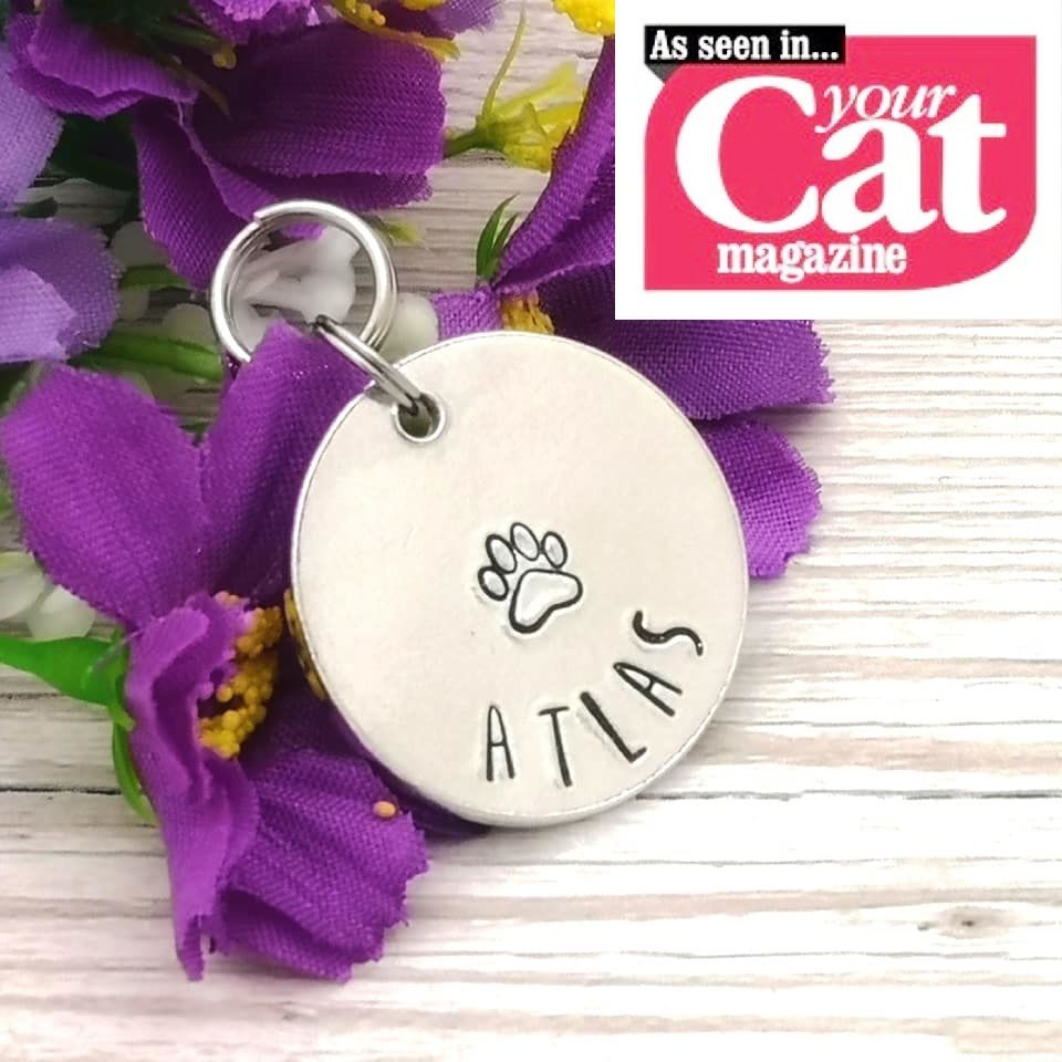 Metal pet ID tag. Shown is front with name & paw print shape