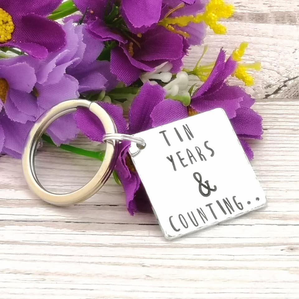 Square metal keyring with the wording, Tin years & counting..