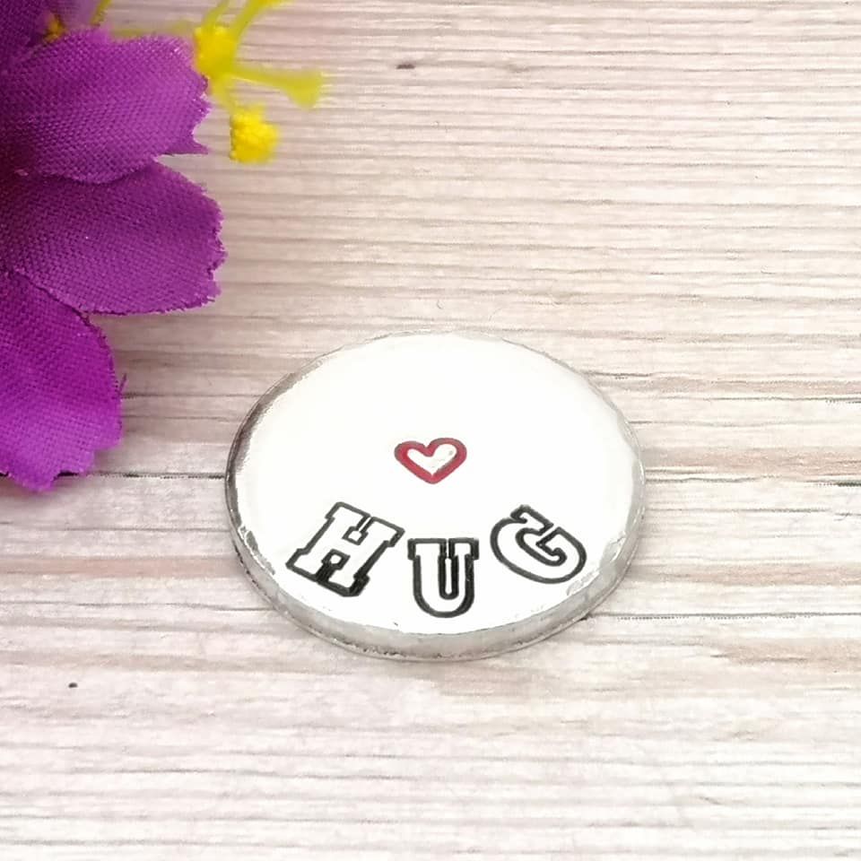 Small chunky metal token with the wording HUG and a small heart