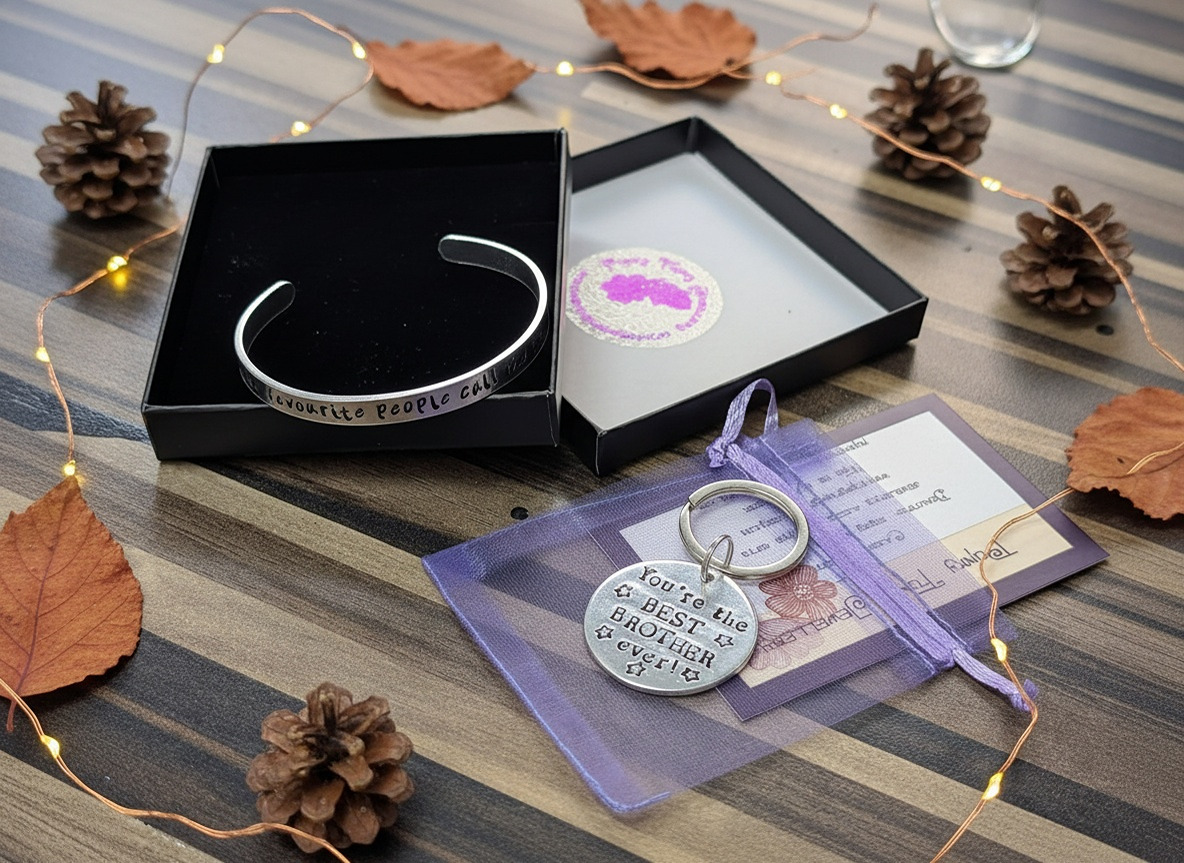 Flat-lay of hand-stamped jewellery gift box and gift bag, surrounded by pinecones and fairy lights, autumn and subtle festive theme.