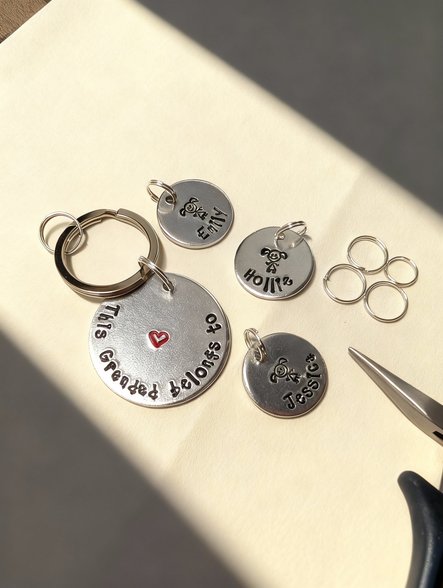 A partially assembled personalised keyring with loose charms, split rings and pliers arranged around it, showing the construction stage of the process.