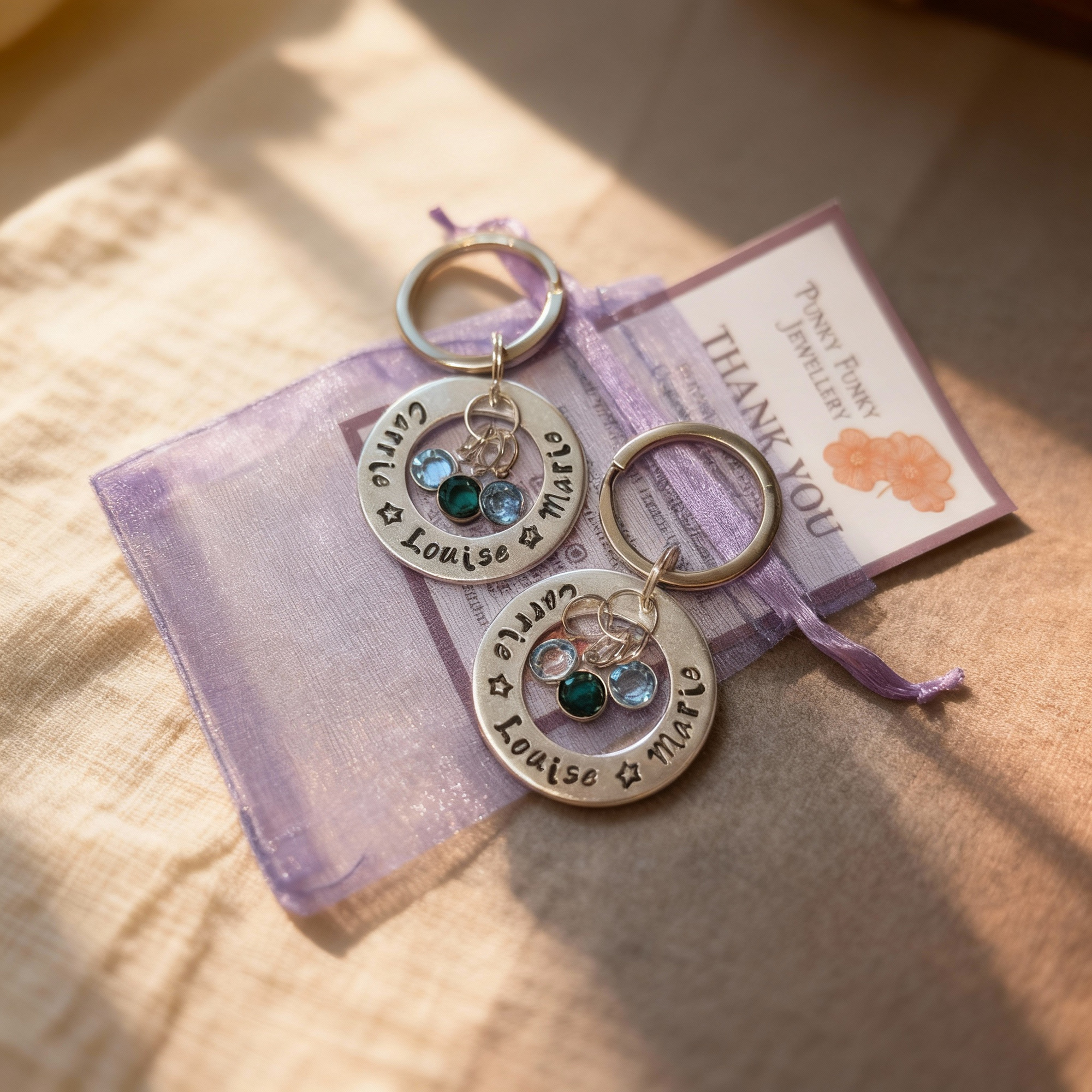 Two finished matching keyrings displayed on an organza gift bag with a thank-you note, presented as a warm, emotional final product.